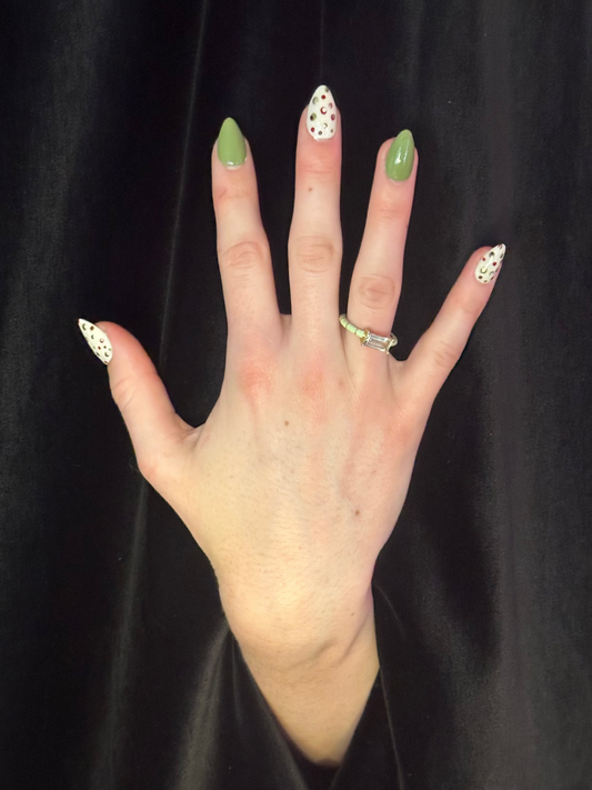Hand with green nail polish and a ring on a black background