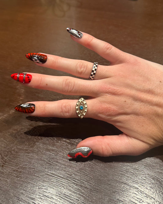 Hand with red and silver nail art on a wooden surface